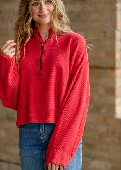 Bright red Free People quarter-zip top with ribbed texture, oversized fit, and dropped shoulders.