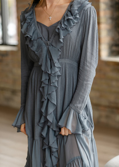 Close-up of slate blue-grey midi dress with cascading front ruffles, textured fabric, and flared sleeve cuffs.