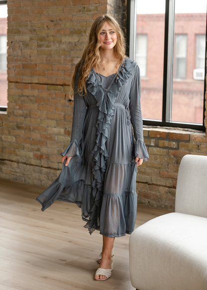 Full-length slate blue-grey midi dress with cascading front ruffles, long sleeves, and tiered flowing skirt.