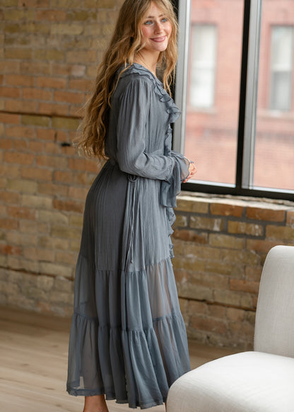 Side detail of slate blue-grey midi dress showing adjustable waist tie, textured fabric, and sheer tiered skirt.