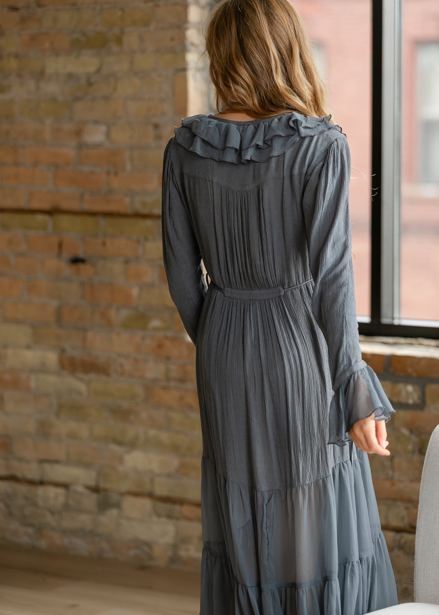Back of slate blue-grey midi dress showing ruffle neckline, gathered back detail, tie waist, and tiered skirt.