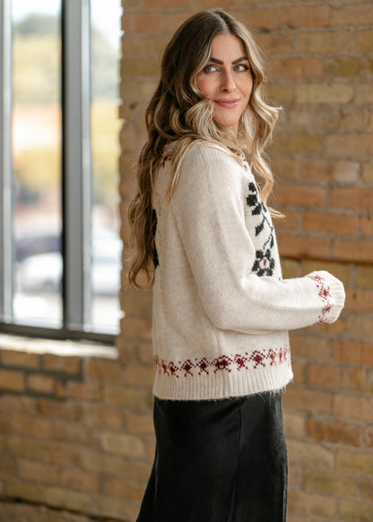 Ivory floral button-up cardigan with black flowers, red geometric trim, and functional buttons.
