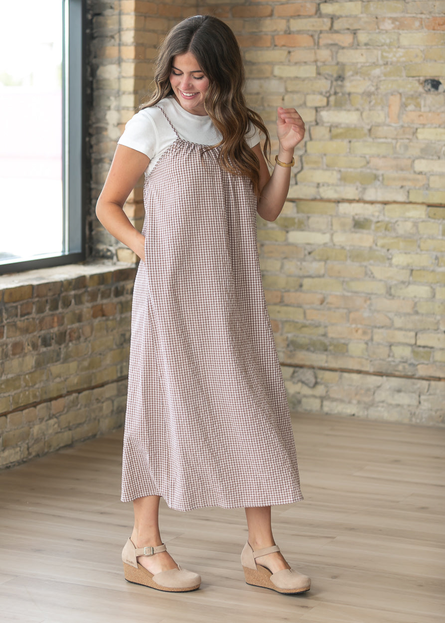 Side view of the taupe gingham cami midi dress showing the relaxed silhouette and pocket detail.