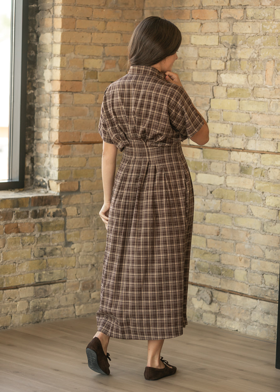 Back of brown plaid midi dress showing the defined waist, pleated A-line skirt, and short sleeves.