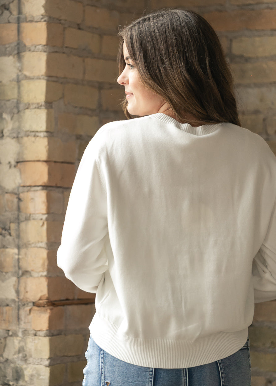 Back of ivory knit cardigan showing the relaxed fit and ribbed hem.
