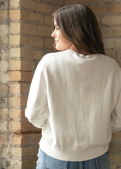 Back of ivory knit cardigan showing the relaxed fit and ribbed hem.
