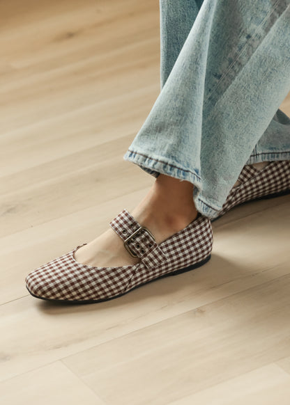 Brown gingham ballet flats with square toe and adjustable buckle strap, styled with light wash jeans.