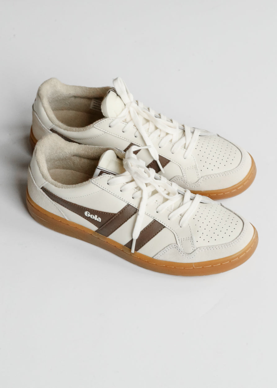 Ivory and brown Gola Eagle '86 sneakers with lace-up front and perforated toe on white background.