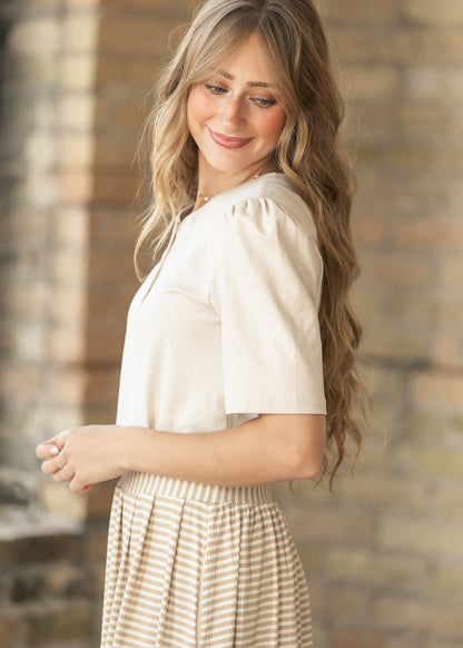 Side view of cream cotton top showing relaxed hip-length fit and elbow-length sleeve.