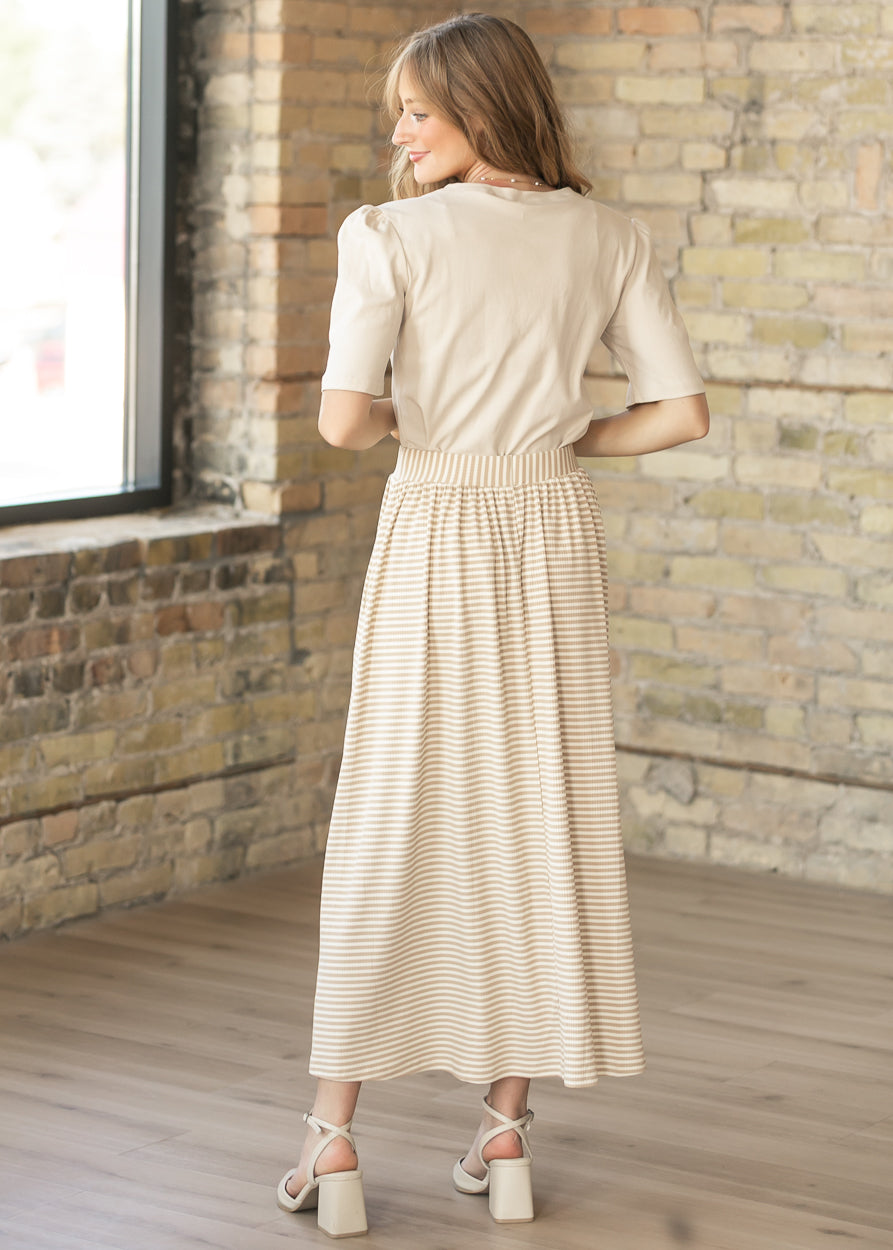 Taupe stripe rib knit midi skirt shown from the back with a cream short sleeve top and neutral heels.