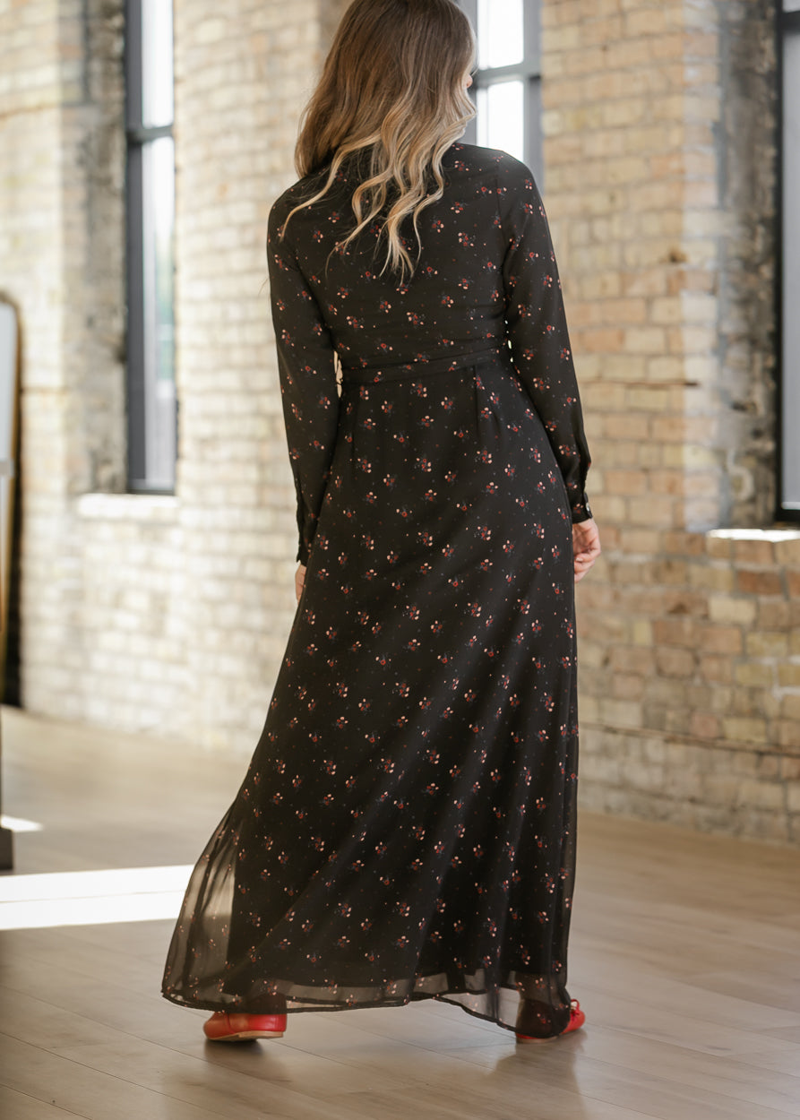 Back of Gracelyn black floral maxi dress showing long sleeves, a matching belt, and a flowing skirt.