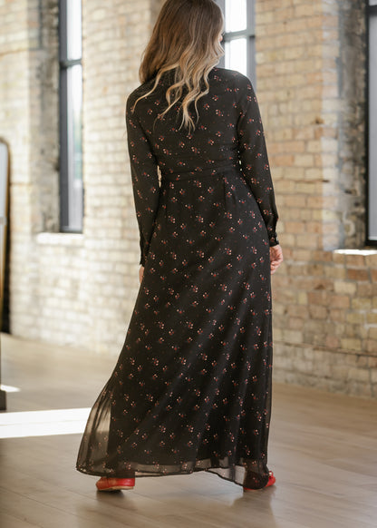 Back of Gracelyn black floral maxi dress showing long sleeves, a matching belt, and a flowing skirt.