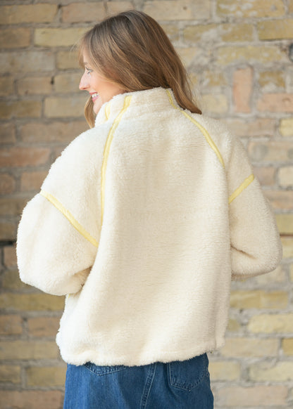 Back of ivory fleece jacket showing contrast seams, dropped shoulders, and relaxed fit.
