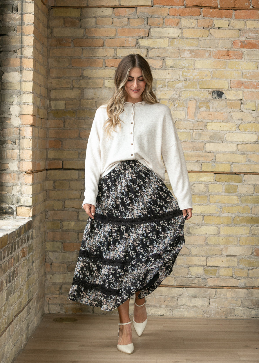 Black floral tiered midi skirt styled with a cream button-front cardigan and heels.