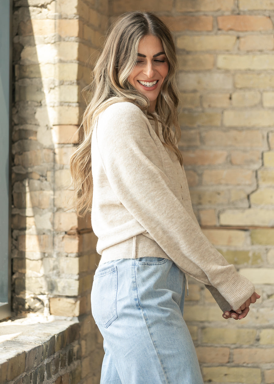 Back of the heather beige henley sweater showing raglan sleeves and a ribbed, hip-length hem.