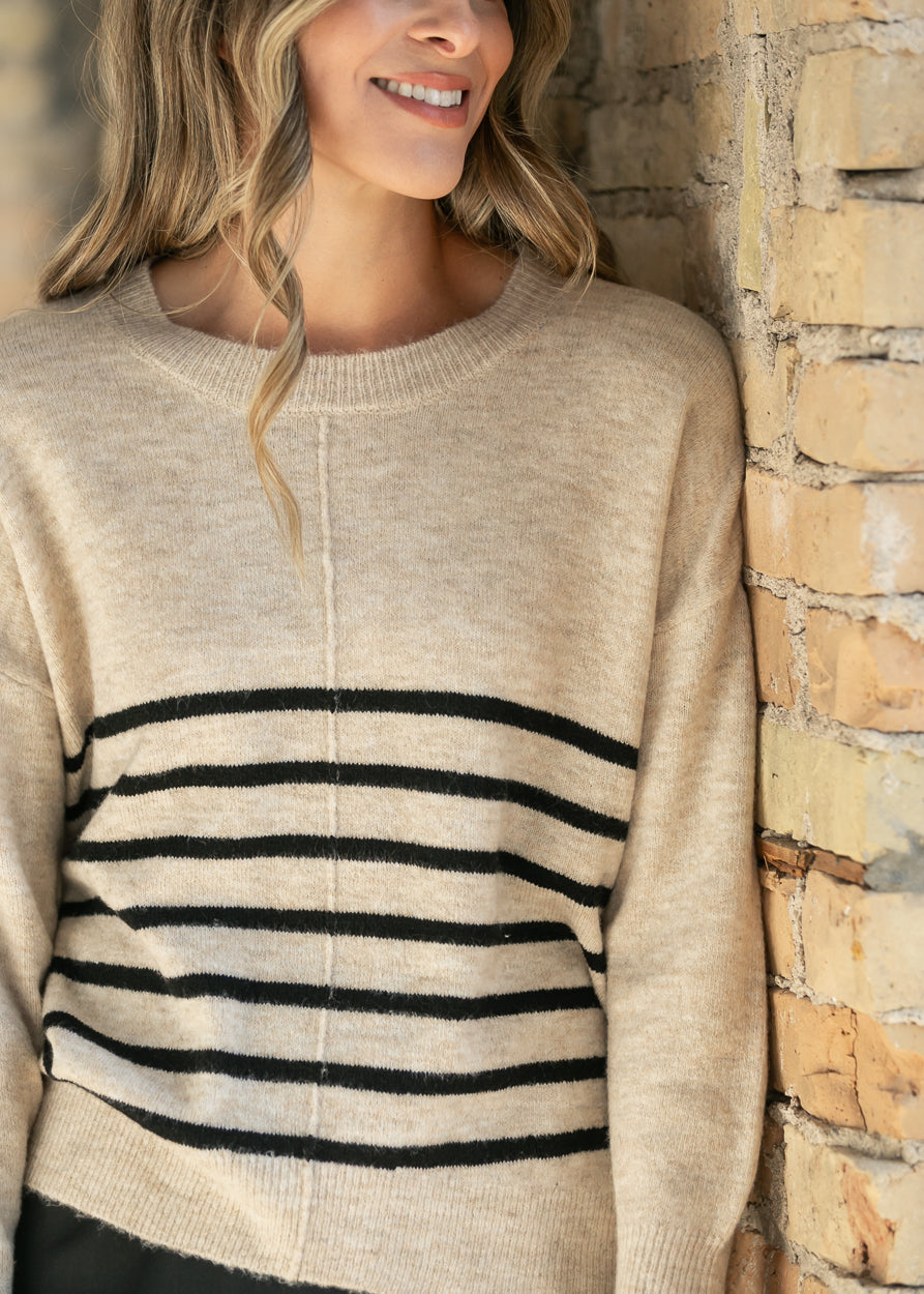 Heather beige sweater with wide drop neckline and black stripe detail at the hem.