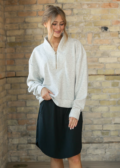 Heather gray quarter zip sweatshirt from the back, showing its cropped, boxy fit and ribbed cuffs.