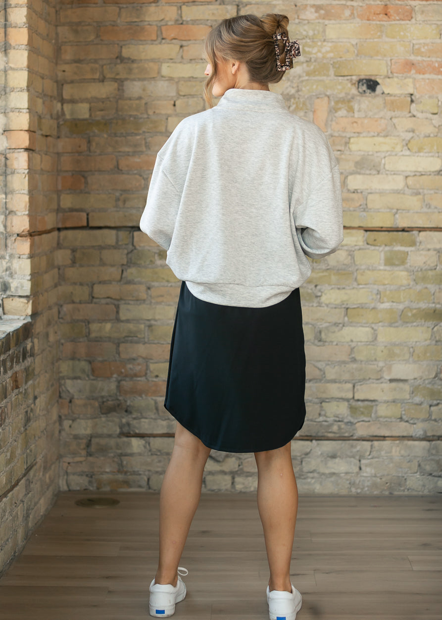 Back view of the heather gray quarter zip sweatshirt with a ribbed hem, styled with a black midi skirt.