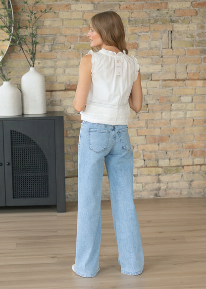 Back view of light wash wide leg denim jeans paired with a white sleeveless blouse.