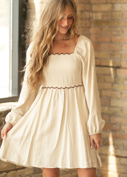 Cream long sleeve midi dress with chocolate brown scalloped trim along the square neckline and waist.