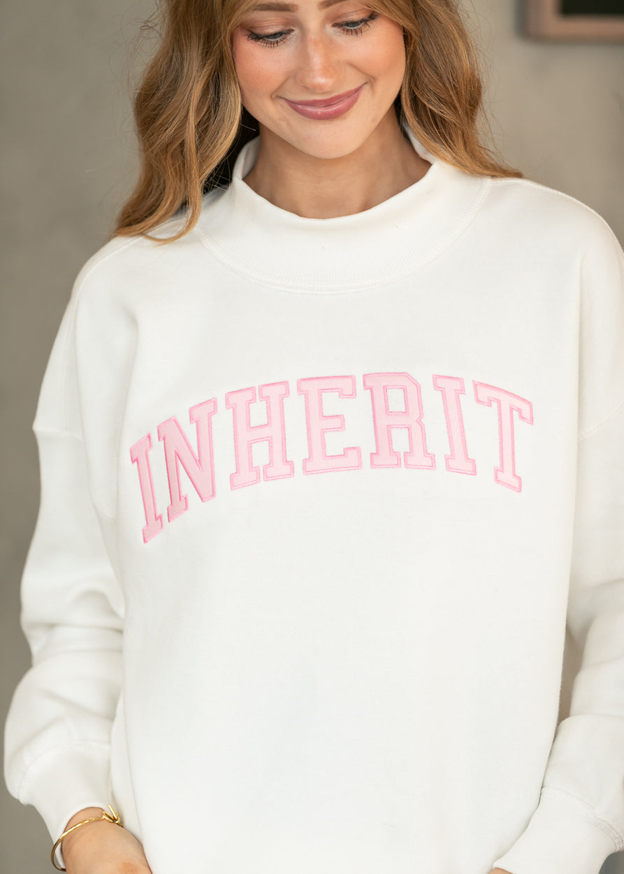 Cream Inherit sweatshirt with pink varsity-style lettering and relaxed long sleeves.