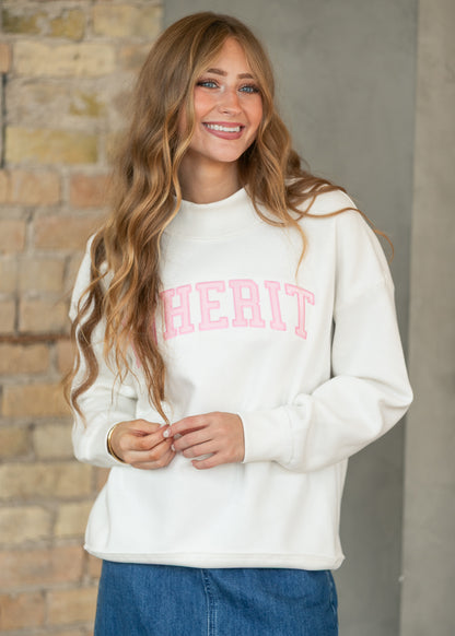 Cream mockneck sweatshirt with pink Inherit lettering, styled with a medium wash denim midi skirt.