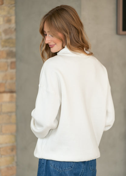 Back of cream mockneck sweatshirt showing the loose fit, drop shoulders, and hip-length silhouette.