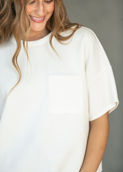 Close-up of ivory scuba top showing the crew neckline and functional front chest pocket.
