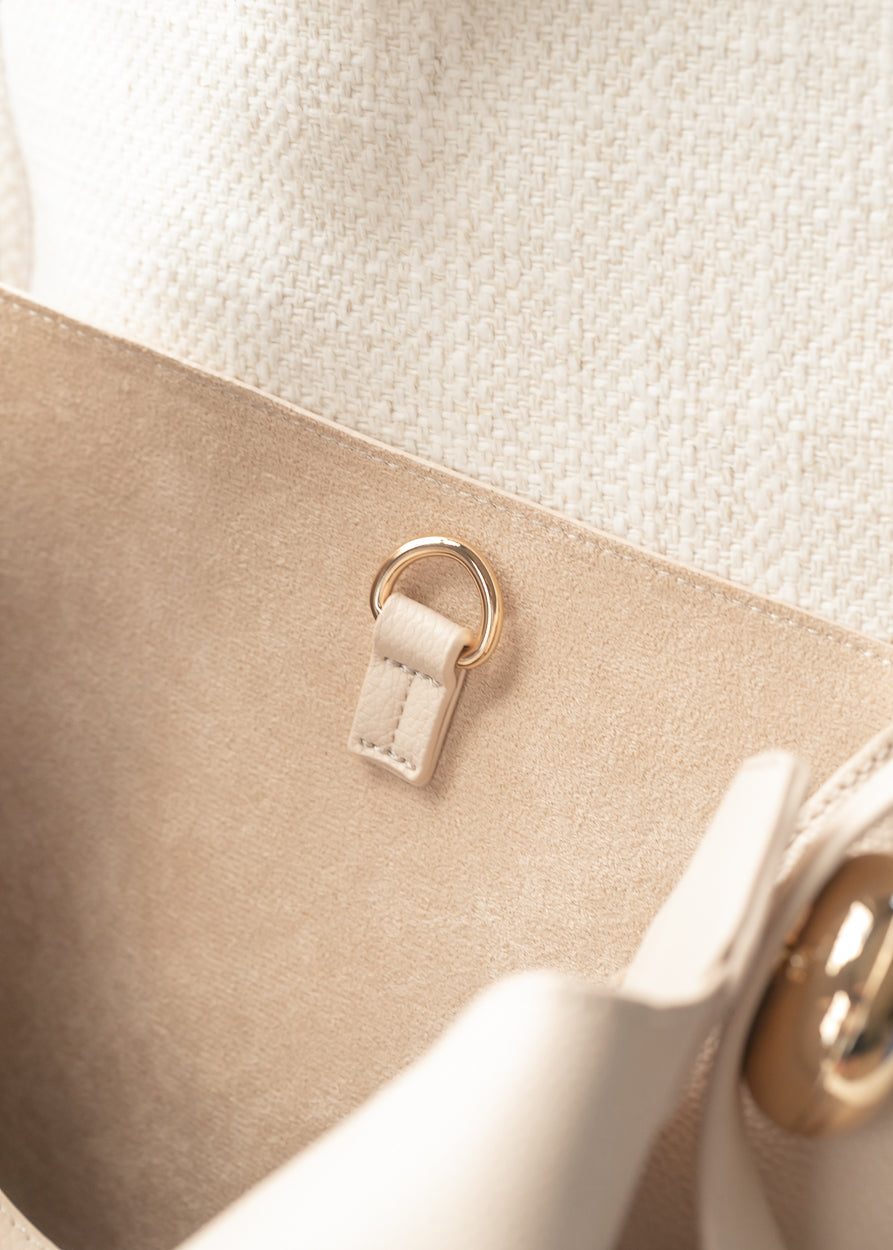 Close-up of ivory tote bag interior with gold-tone hardware and soft textured lining.