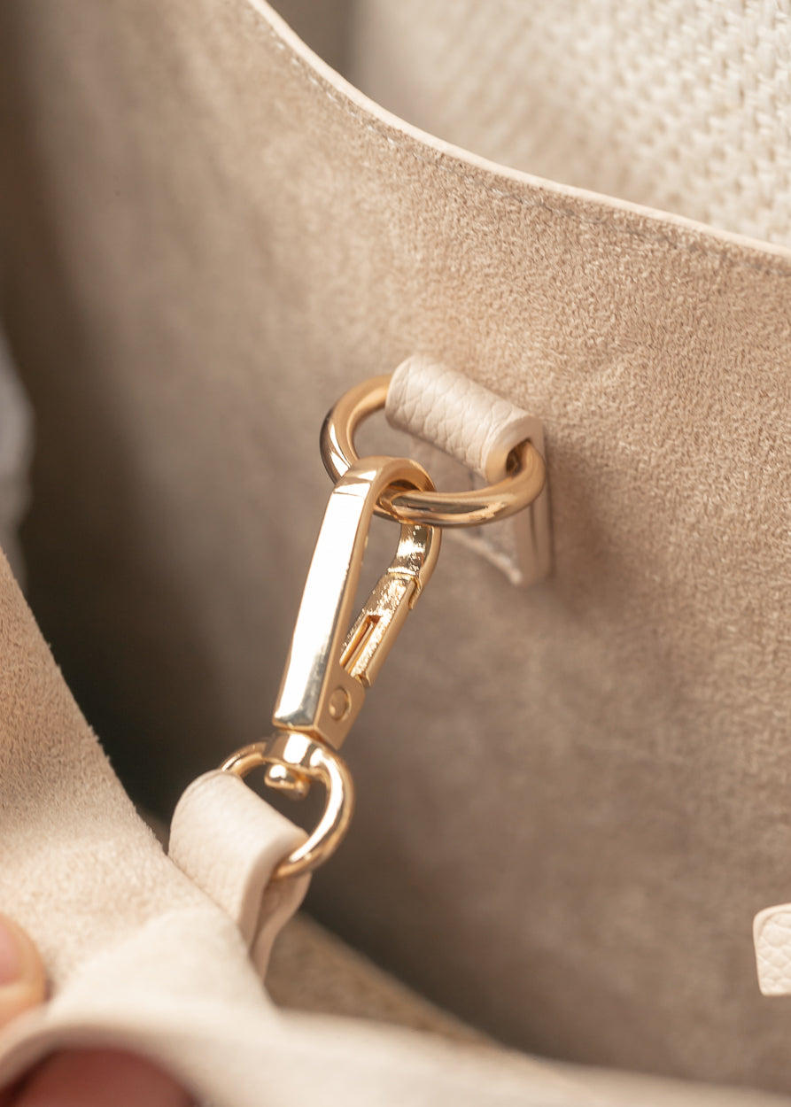Interior detail of ivory tote bag showing removable strap attachment and suede-look lining.
