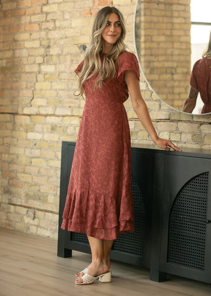 Rust short sleeve jacquard midi dress styled with cream woven heels beside a round mirror.