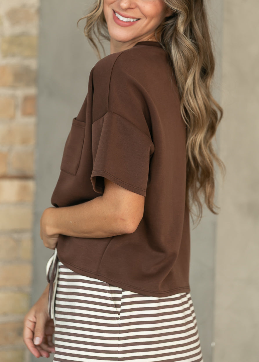 Side view of chocolate scuba top with relaxed short sleeves and a loose boxy silhouette.