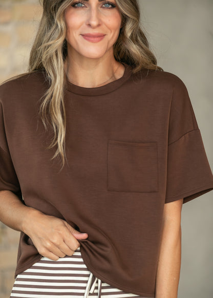 Close-up of chocolate crew neck scuba top showing the crew neckline and functional front chest pocket.