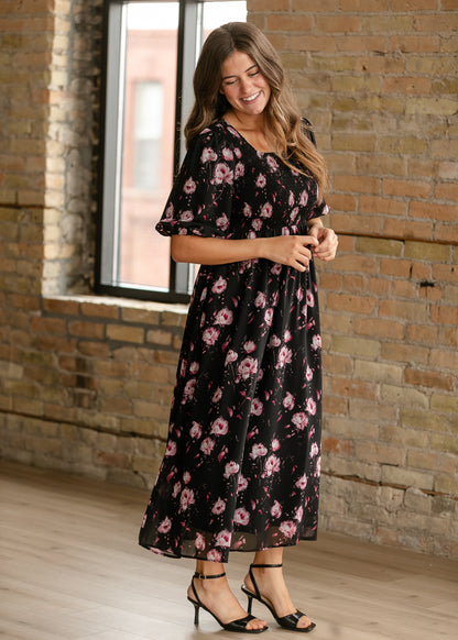 Black floral maxi dress with square neckline, smocked bodice, and softly gathered skirt.