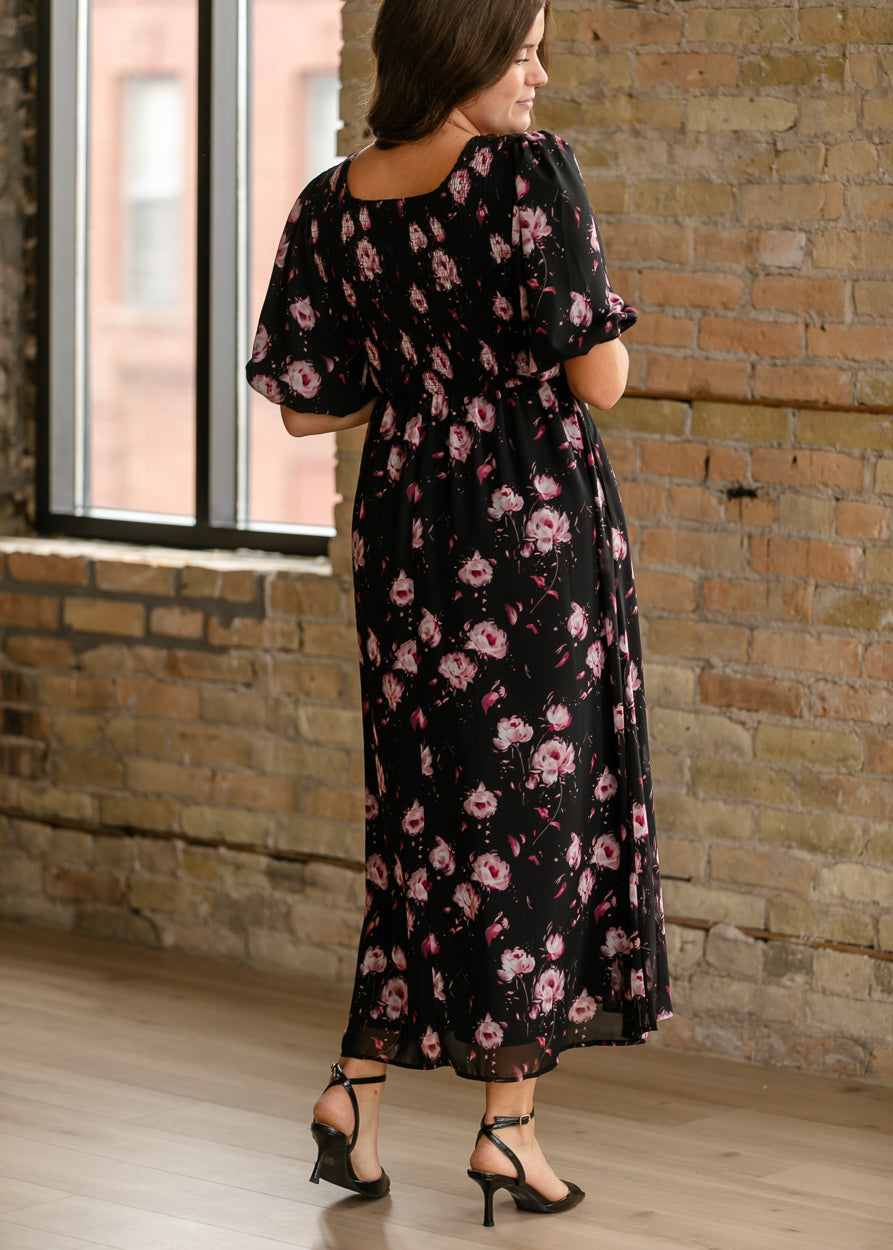Back of black floral maxi dress showing the smocked bodice and flowing ankle-length skirt.