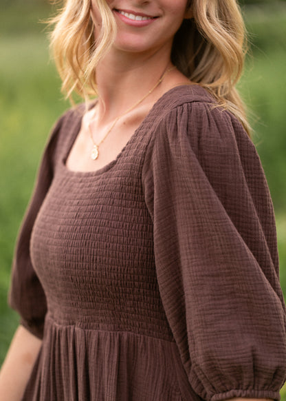 Close-up of chocolate cotton gauze dress showing the neckline, sleeve, and smocked bodice.