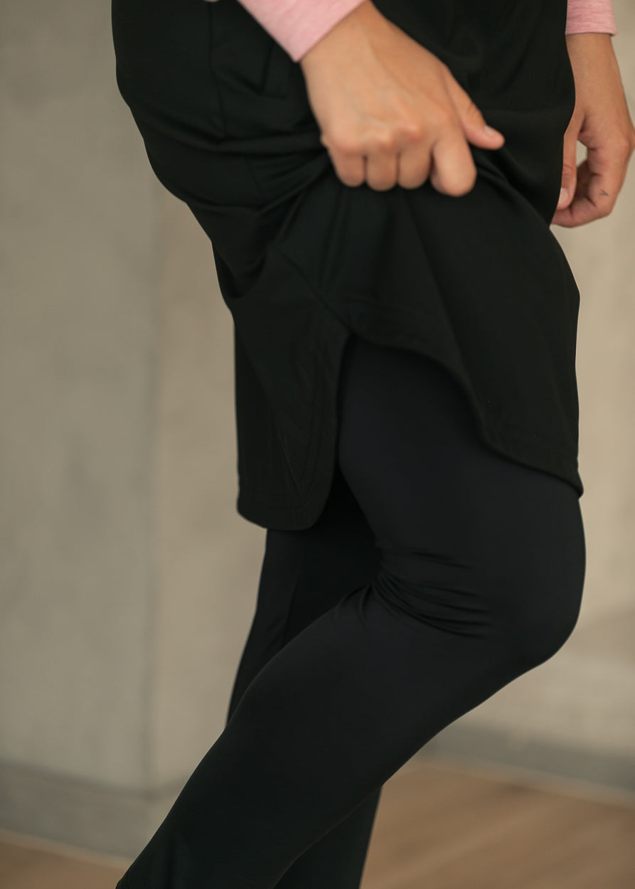 Black sport skirt lifted to show smooth built-in full-length leggings underneath.