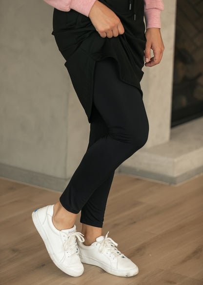 Built-in black leggings shown beneath the Kenedi sport skirt, styled with white sneakers.
