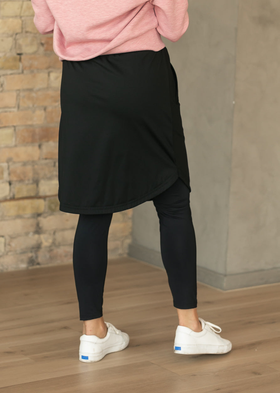 Back of black Kenedi sport skirt with full-length leggings and curved tulip hem.