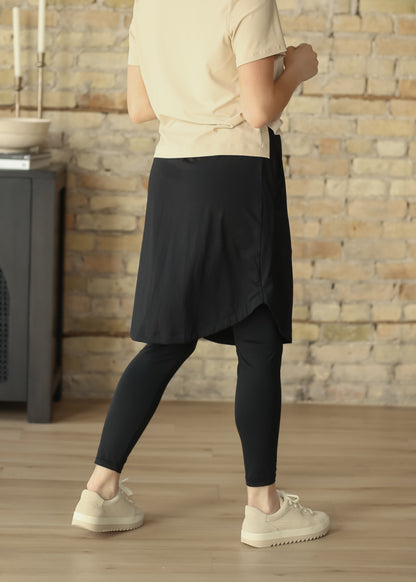 Back view of black athletic skirt with built-in leggings and curved tulip hem.