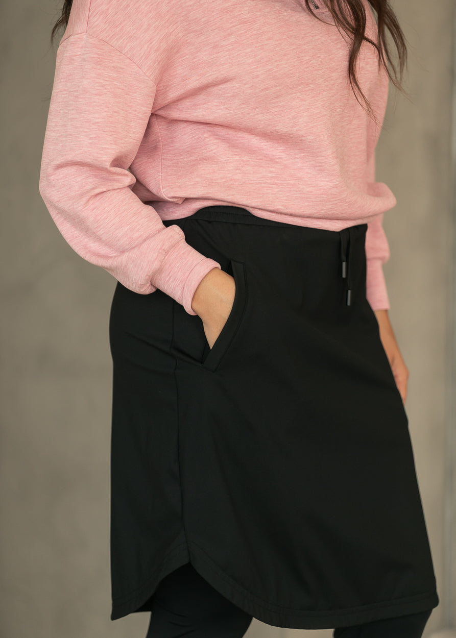 Close-up of black Kenedi sport skirt showing side pocket, drawstring waist, and tulip hem.