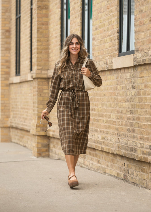 Kimberly brown plaid midi dress with long sleeves, button front, and tie waist styled with neutral flats.