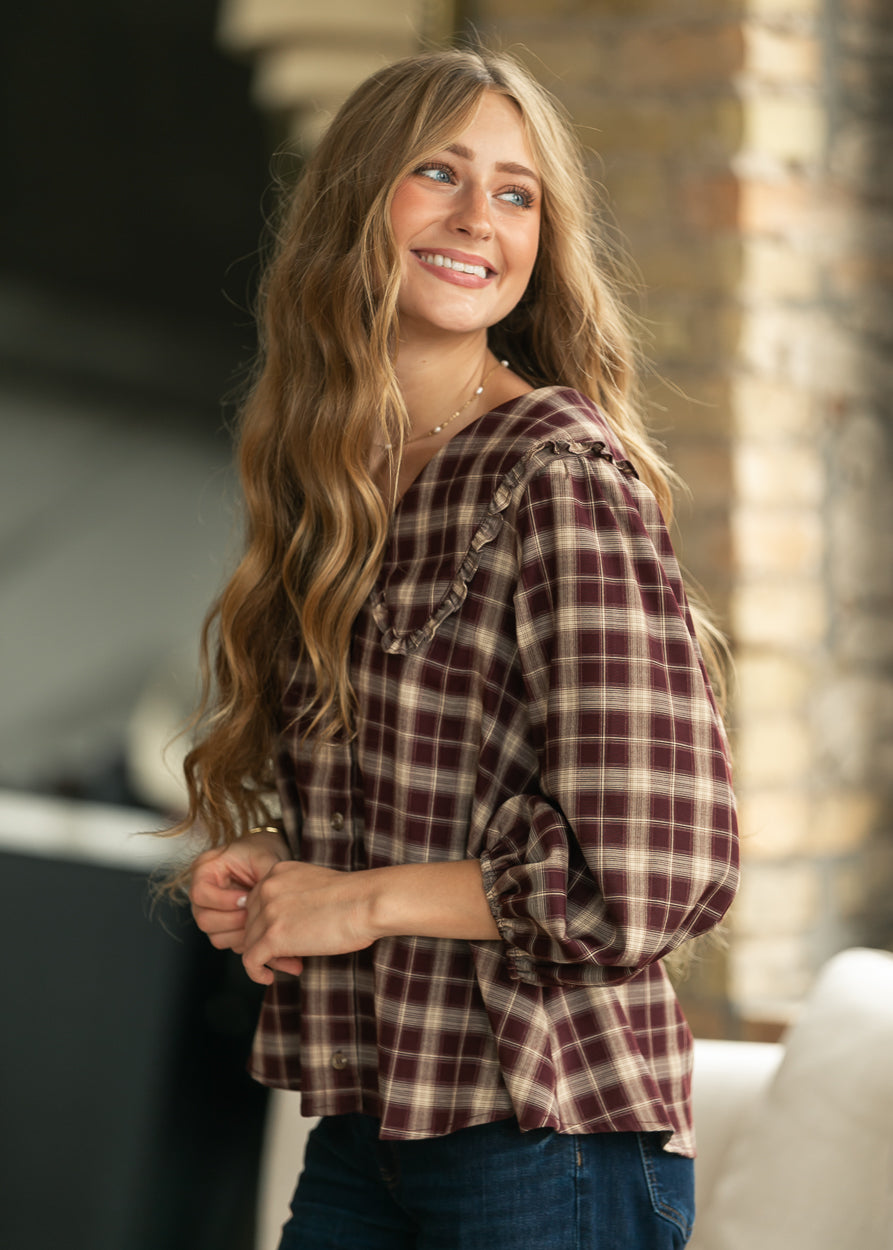 Burgundy and cream plaid V-neck blouse with ruffle collar, styled with dark wash denim.