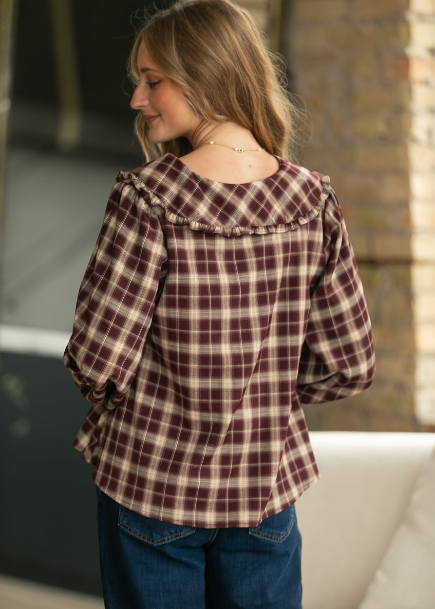 Back of burgundy and cream plaid blouse showing wide ruffle collar and three-quarter sleeves.