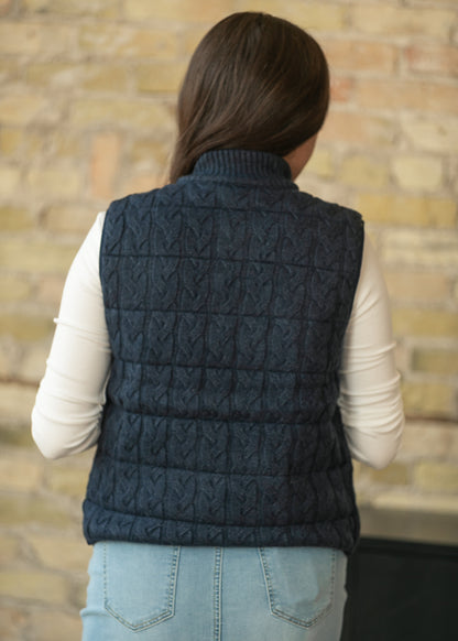 Back of navy sleeveless vest showing cable-knit quilted texture and hip-length hem.