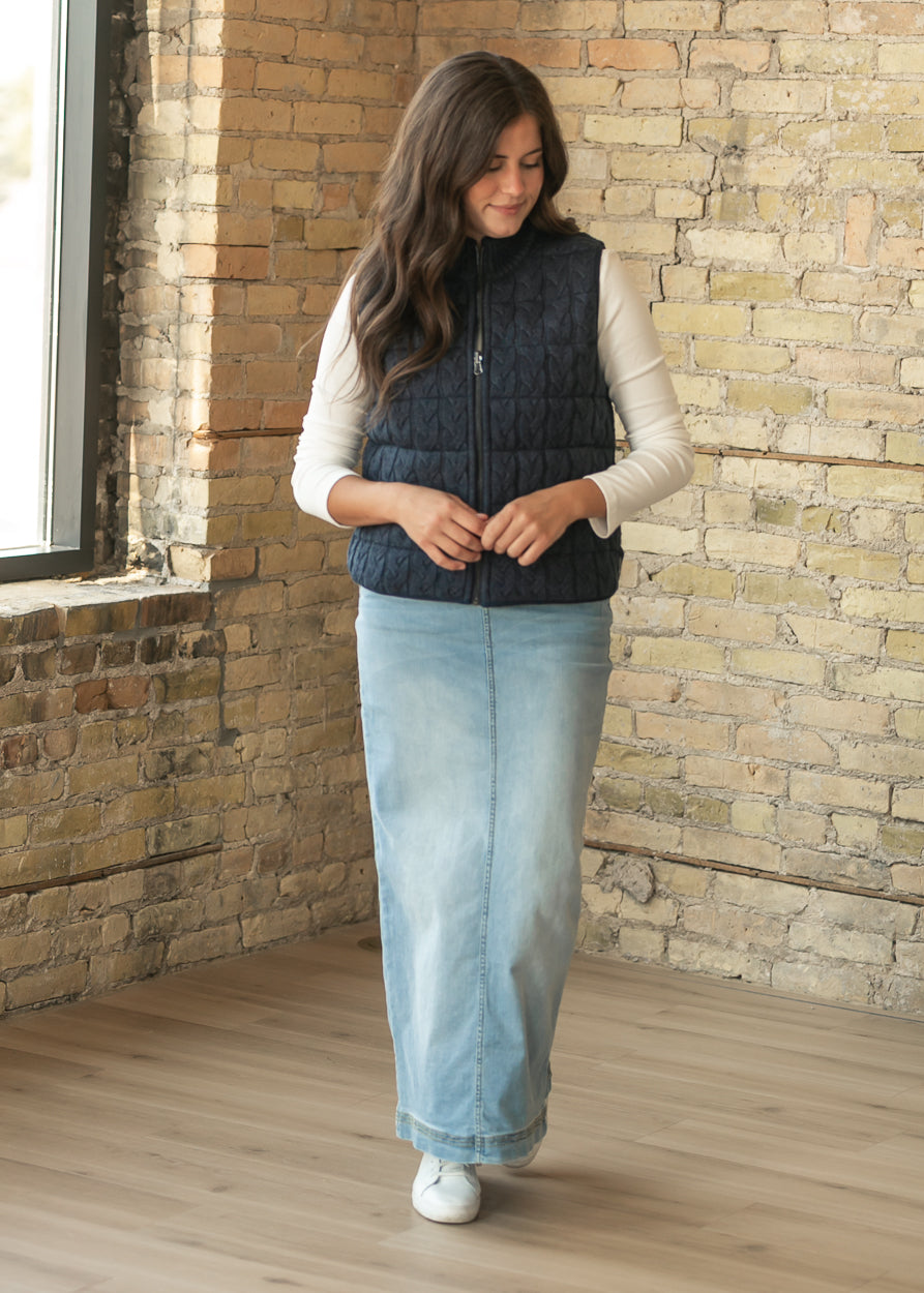 Navy sleeveless reversible vest styled with a cream long sleeve top and light wash denim maxi skirt.