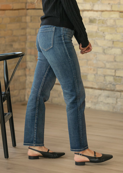 Dark wash slim jeans from the side and back, showing the slim leg and ankle-skimming hem.