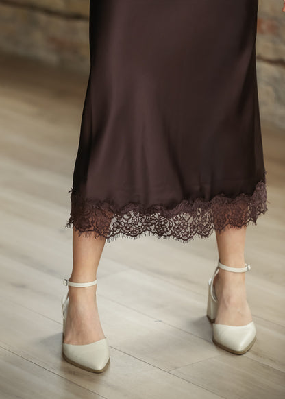 Close-up of chocolate brown satin skirt showing the delicate floral lace hem