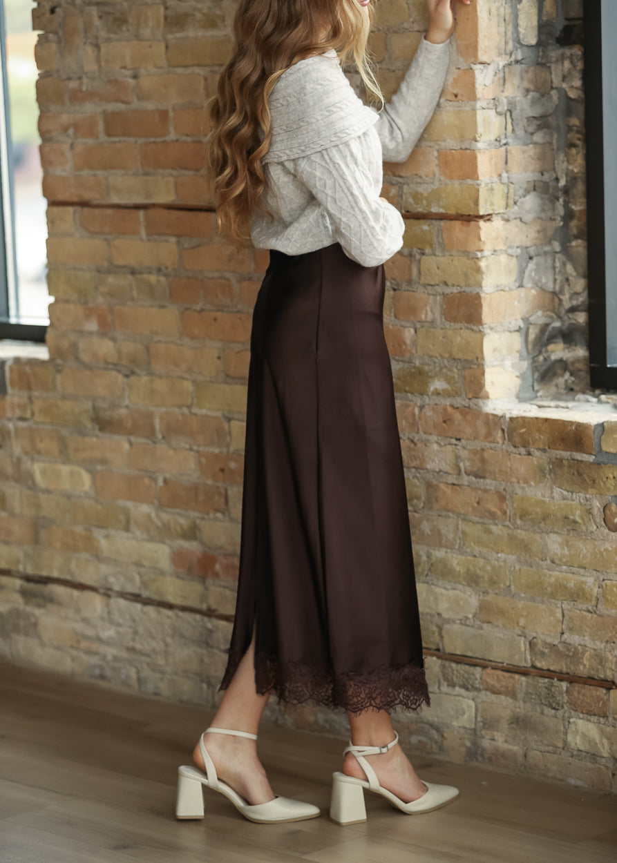 Side view of chocolate brown satin midi skirt showing the smooth fitted silhouette