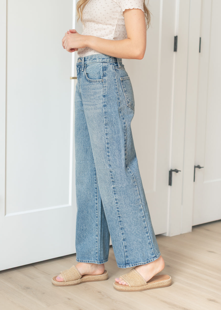 Side view of medium wash barrel jeans paired with woven slide sandals
